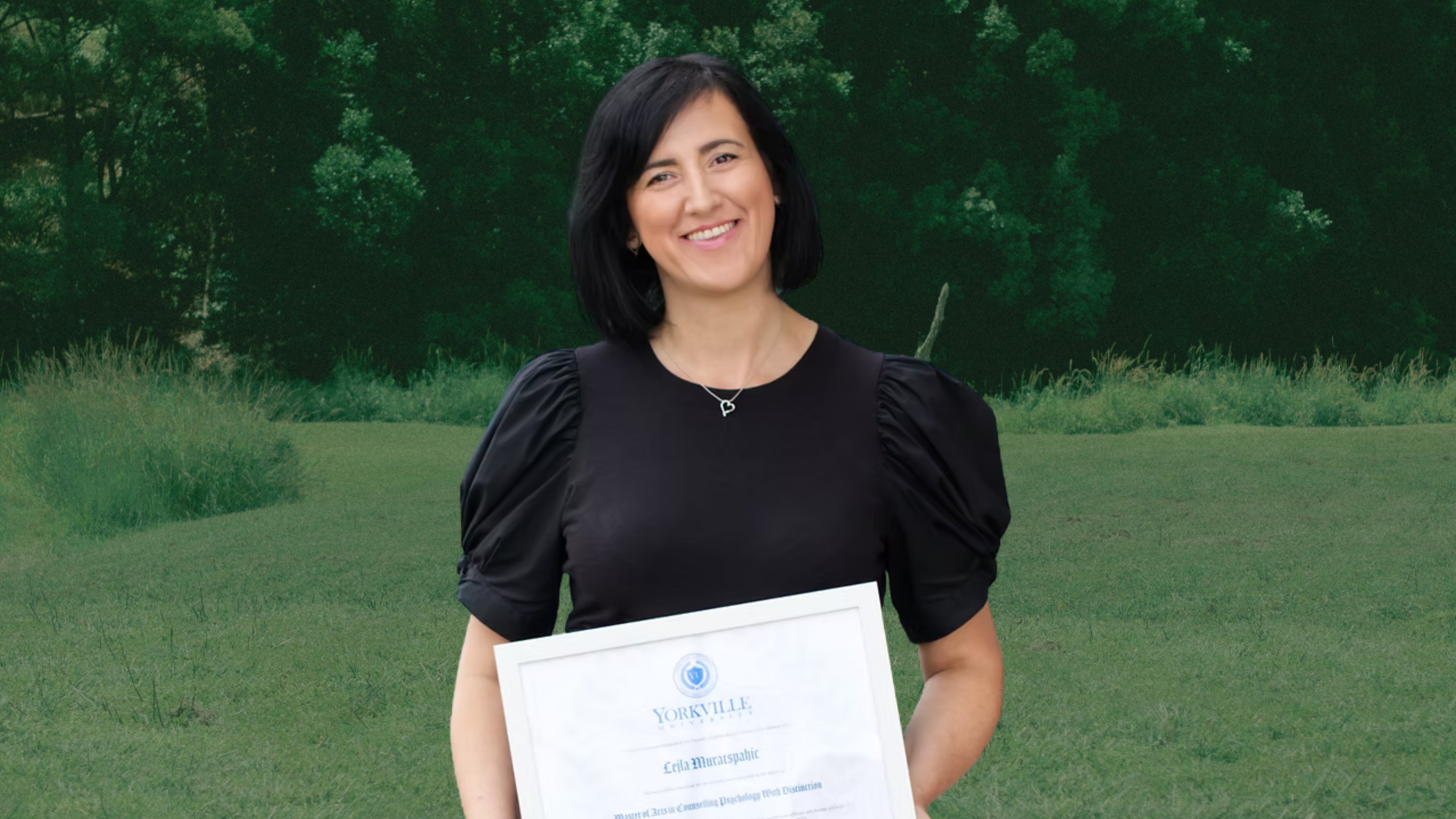 Lejla standing outdoors holding her Master's degree certificate in Counselling Psychology